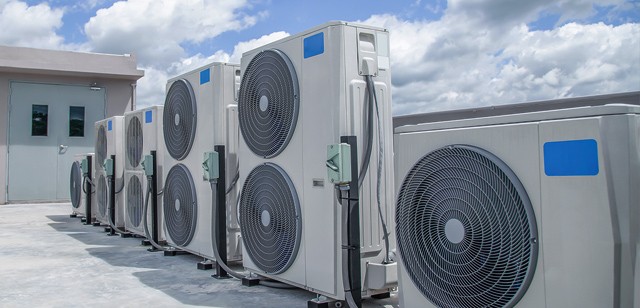 Image of industrial sized HVAC systems outside with clouds and a blue sky in the background.